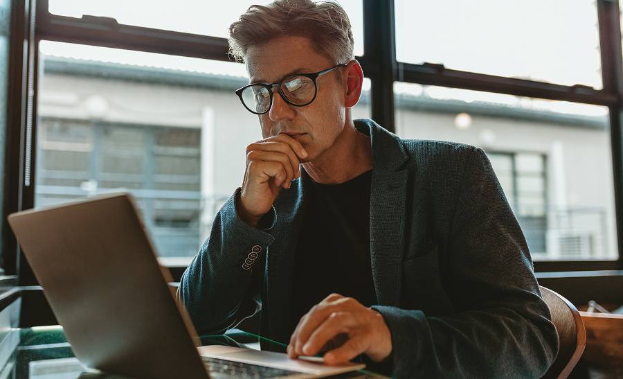 A male employee thinking while using a laptop