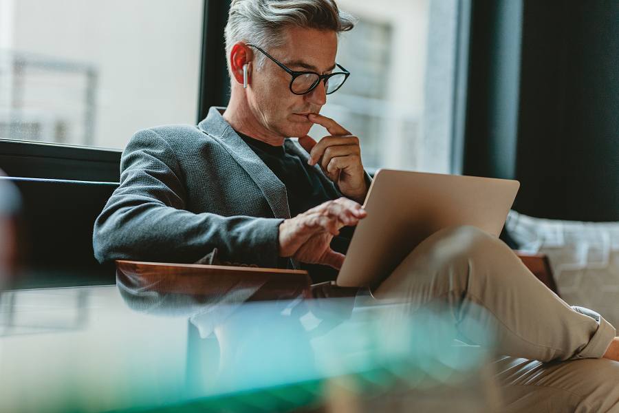 A male employee thinking while using a laptop